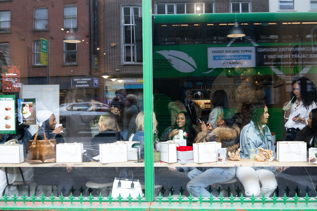 Guests enjoying Flowers & Coffee inside Ada Coffee, seen through the café window.
